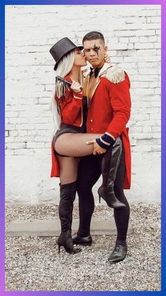 a man and woman dressed up in costume kissing each other while standing next to a brick wall