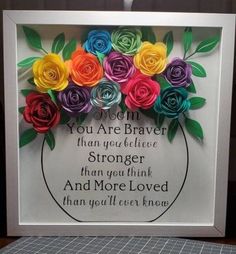 paper flowers in a white frame with the words, you are brave than you believe and more loved than you'll ever know