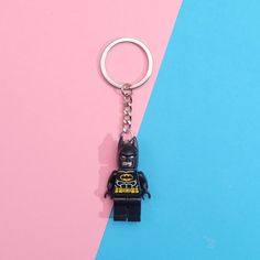 a lego batman keychain on a pink and blue background