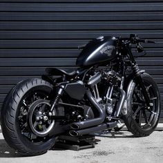 a black motorcycle is parked in front of a garage door on a metal platform with wheels