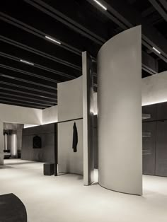 an empty room with white walls and black furniture in the center is lit by recessed lights