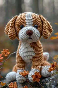 a crocheted dog sitting on top of a rock in front of some flowers