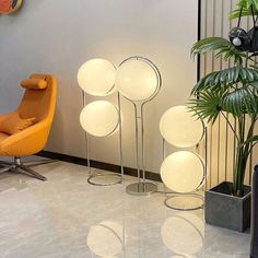 a room with two chairs and three lamps on the floor next to each other in front of a plant