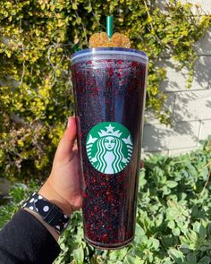 a person holding up a starbucks cup with red sprinkles