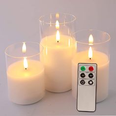 four lit candles with remote control on white background