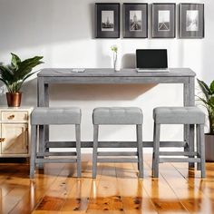 a table with three chairs and a laptop on it in front of some framed pictures