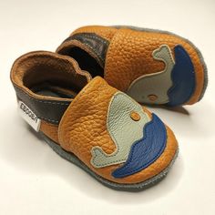 a pair of brown and blue baby shoes on a white surface with the bottom part showing