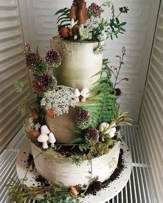 a three tiered cake decorated with plants and mushrooms