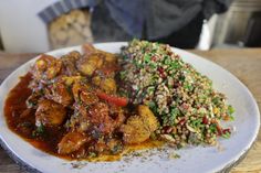 a white plate topped with meat and veggies next to a pile of rice