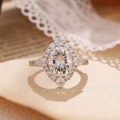 an oval cut diamond ring on top of a lace doily