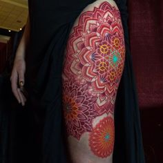 a woman's leg with red and orange flowers on it, in front of a maroon background