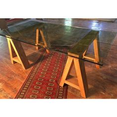 a glass table sitting on top of a wooden floor next to a red rug in front of it