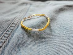 a yellow and white beaded bracelet sitting on top of a blue jean jacket,