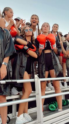 some girls are standing on the bleachers with their boxing gloves in front of them