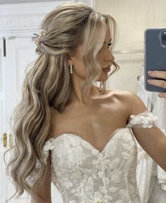 a woman in a wedding dress taking a selfie with her cell phone while looking into the mirror