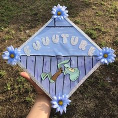 someone is holding up a kite decorated with blue flowers and the words autumn on it