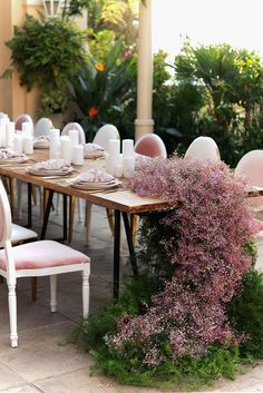 the table is set with pink and white chairs