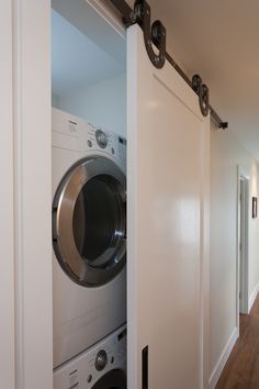 a washer and dryer are in the hallway next to an open closet door