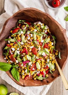 a wooden bowl filled with corn and vegetables