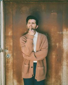 a man standing in front of a door with his hand on his mouth and looking at the camera