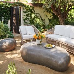 an outdoor living area with couches, tables and flowers in vases on the table