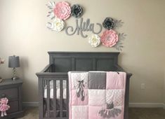 a baby crib with pink and gray flowers on the wall