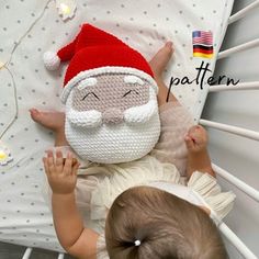 a baby laying on top of a bed next to a stuffed santa clause