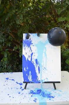 an easel sitting on top of a white table covered in blue and white paint