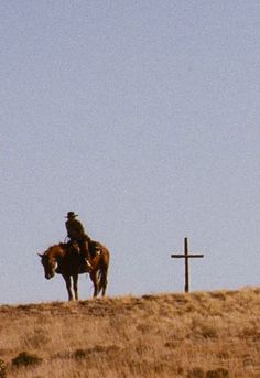 two people on horses near a cross in the desert