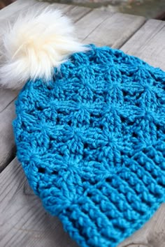 a blue knitted hat with a white pom - pom on top of it