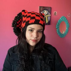 a young woman wearing a knitted hat in front of a wall with pictures on it