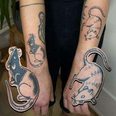 two people with tattoos on their arms holding up small stickers that look like mice