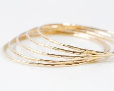 Elevate your style effortlessly with our Handmade 14K Gold Filled Stacking Bangles. These are sold individually. Increase the quantity at add to cart to build your stack. Handcrafted from exquisite 14K gold filled material, these bangles feature a unique hand-hammered texture, adding a touch of glamour and sophistication to any ensemble. Individually handmade by our team of talented artisans, these bangles provide a sensory delight with their smooth touch, delicate chime, and graceful movement a Adjustable Stackable Gold-plated Bangle, Stackable 14k Yellow Gold Filled Bracelet, Hammered Yellow Gold Bangle For Everyday, Everyday Hammered Yellow Gold Bangle, Stackable Dainty 14k Gold Bangle, Dainty Stackable 14k Gold Bangle, Dainty 14k Gold Stackable Bangle, Adjustable Stackable 14k Gold Bangle, Gold Stackable Bangle