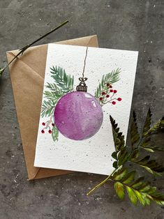 an ornament on a card with greenery