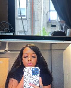 a woman taking a selfie in front of a computer screen with her cell phone