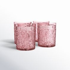 two pink glass tumblers sitting next to each other on a white surface with shadows