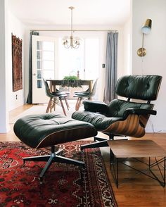 an eames chair and ottoman in the middle of a living room with a rug on the floor