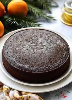 a chocolate cake sitting on top of a white plate next to an orange and pine tree