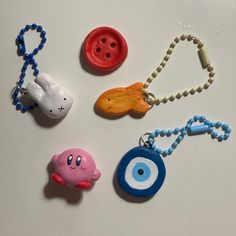 four different types of key chains on a white surface with beads and buttons attached to them