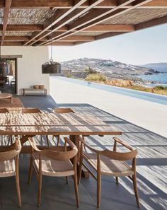 an outdoor dining area with wooden tables and chairs, overlooking the ocean in the distance