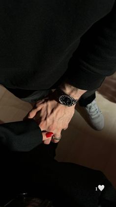 two people holding hands in the dark with one person wearing a watch on their wrist