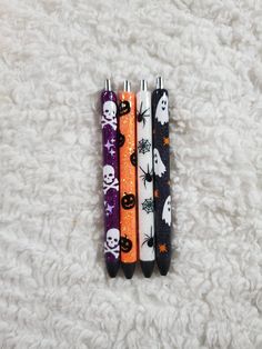 three halloween themed pens sitting on top of a white carpet