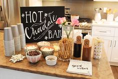 a kitchen counter topped with cups and bowls filled with food next to a sign that says hot chocolate bar