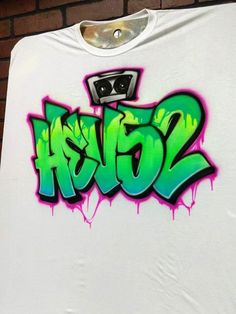 a white t - shirt with green and purple spray paint on it's chest