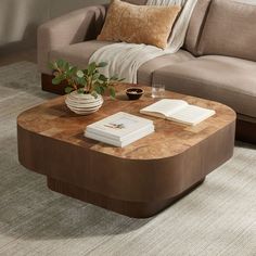 a living room with a couch, coffee table and books on the end tables in front of it