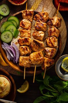 chicken skewers with cucumbers and pickles on a wooden platter