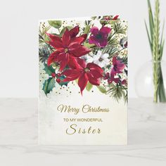 a christmas card with poinsettis and greenery on the front, sitting next to a vase of flowers