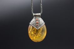 A very unique Hand made Silver Pendant with a replica Amber. Amber is used by Tibetans for centuries. High-quality amber is rare and expensive. The replica is commonly used with Silver as jewelry. In this piece, amber is decorated beautifully with carved silver that has an Auspicious symbol conch shell, flora pattern and coral cabs. Wt: 26g Origin- Nepal 20th c Traditional Oval Yellow Jewelry, Traditional Yellow Oval Jewelry, Antique Engraved Amber Jewelry, Handmade Amber Necklace For Collectors, Traditional Amber Jewelry With Carved Details, Vintage Carved Amber Jewelry, Vintage Amber Carved Jewelry, Collectible Bohemian Amber Jewelry, Traditional Amber Oval Jewelry