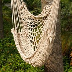 a white rope hammock hanging from a tree