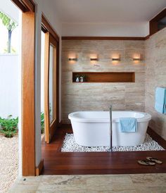 a white bath tub sitting on top of a wooden floor next to a bathroom window